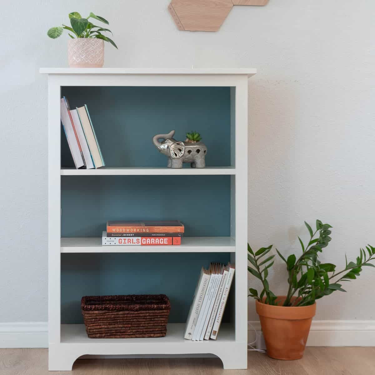 Simple plywood bookshelf painted white with blue background