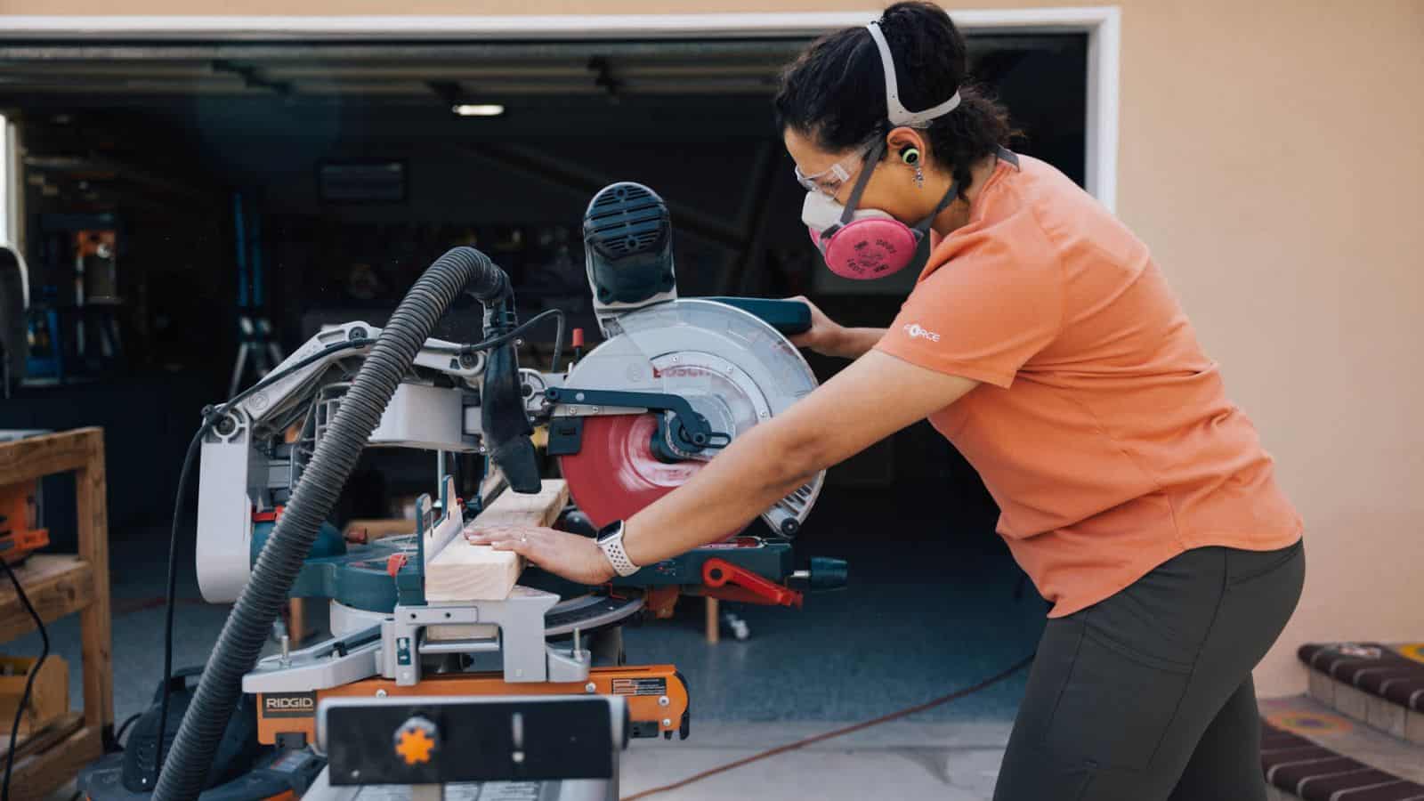 Anika wearing safety gear using a miter saw