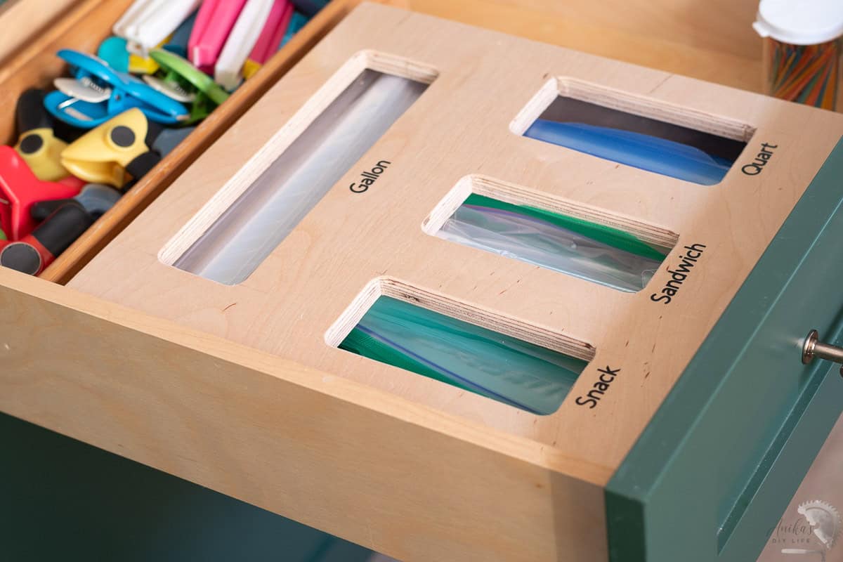 Wooden ziploc bag organizer in a green drawer with food storage bags in it. 