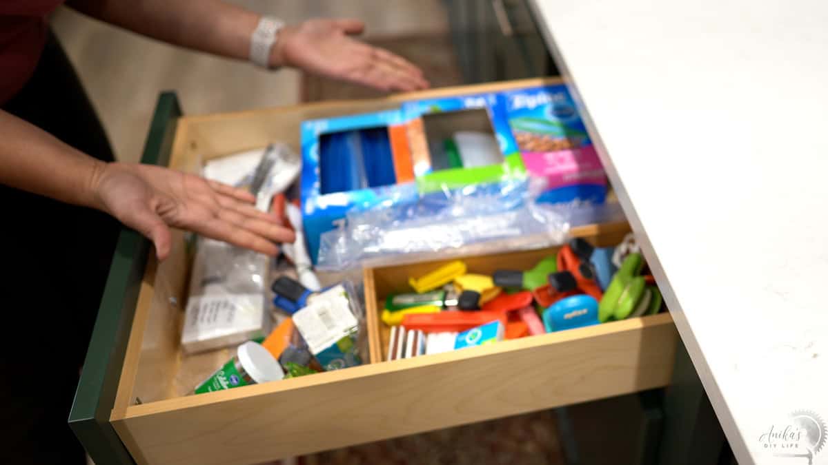 The kitchen drawer before with various original cardboard boxes and a lot of mess.
