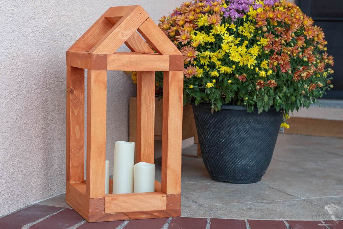 DIY house shaped wooden lantern on porch with candles inside