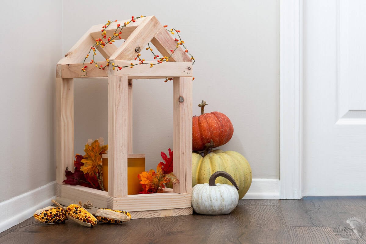 DIY house shaped wood lantern with pumpkins around it