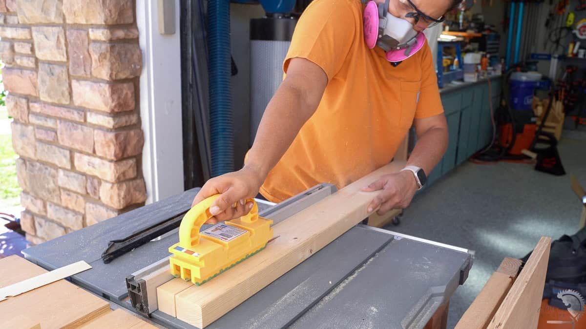 Anika ripping a 2x6 board into 2x2 on a table saw