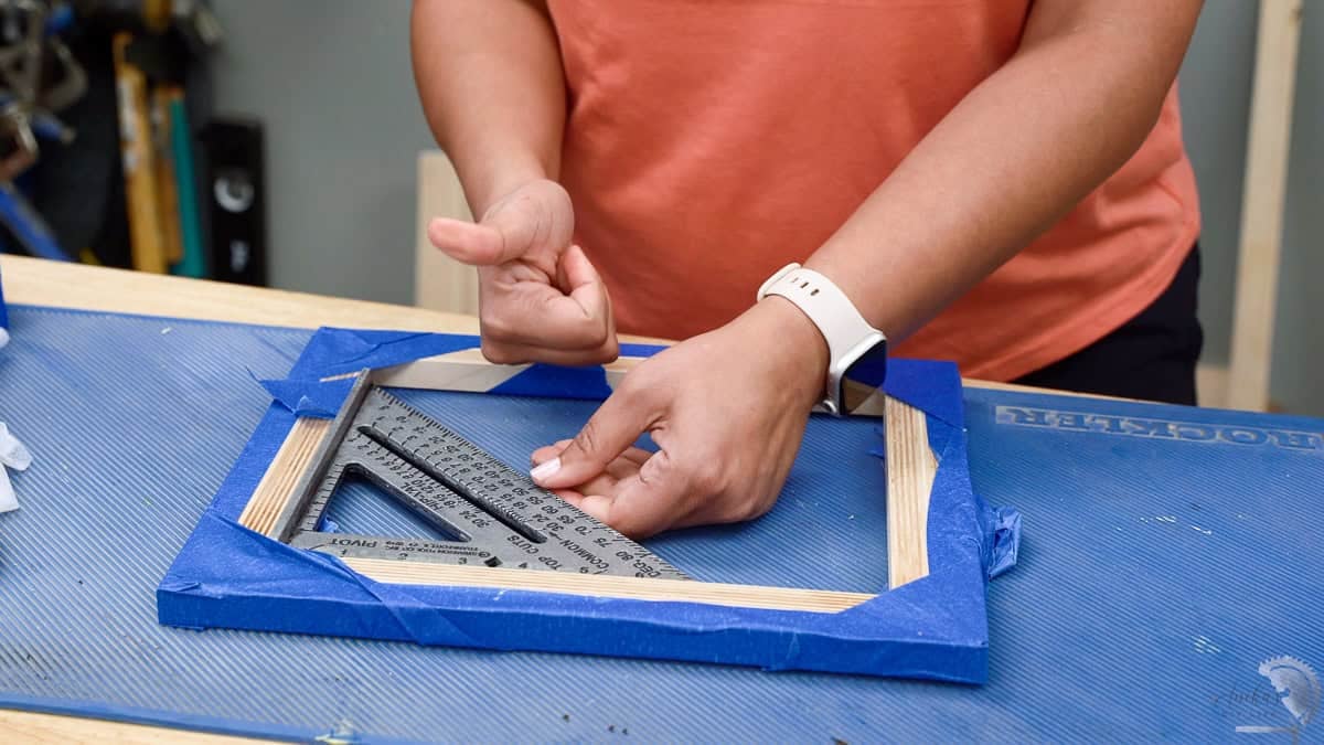 Woman checking the plywood picture frame for square