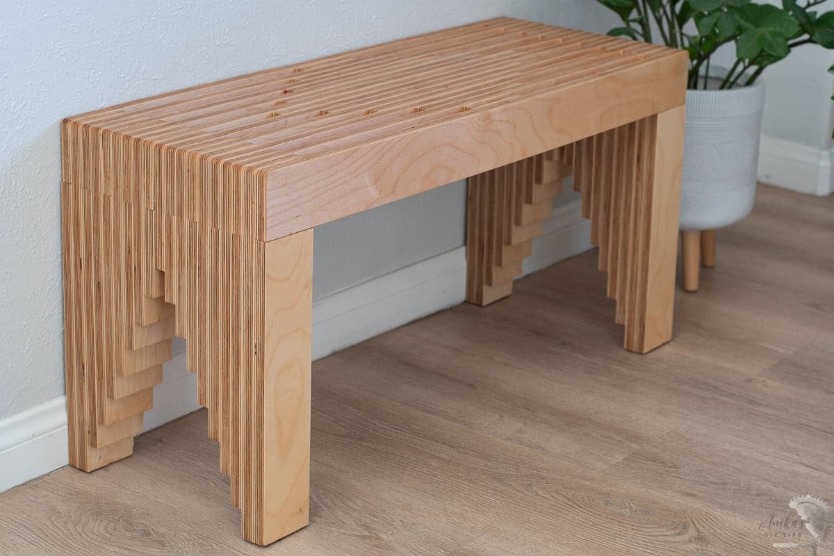 Stacked plywood diy bench in front of gray wall. 