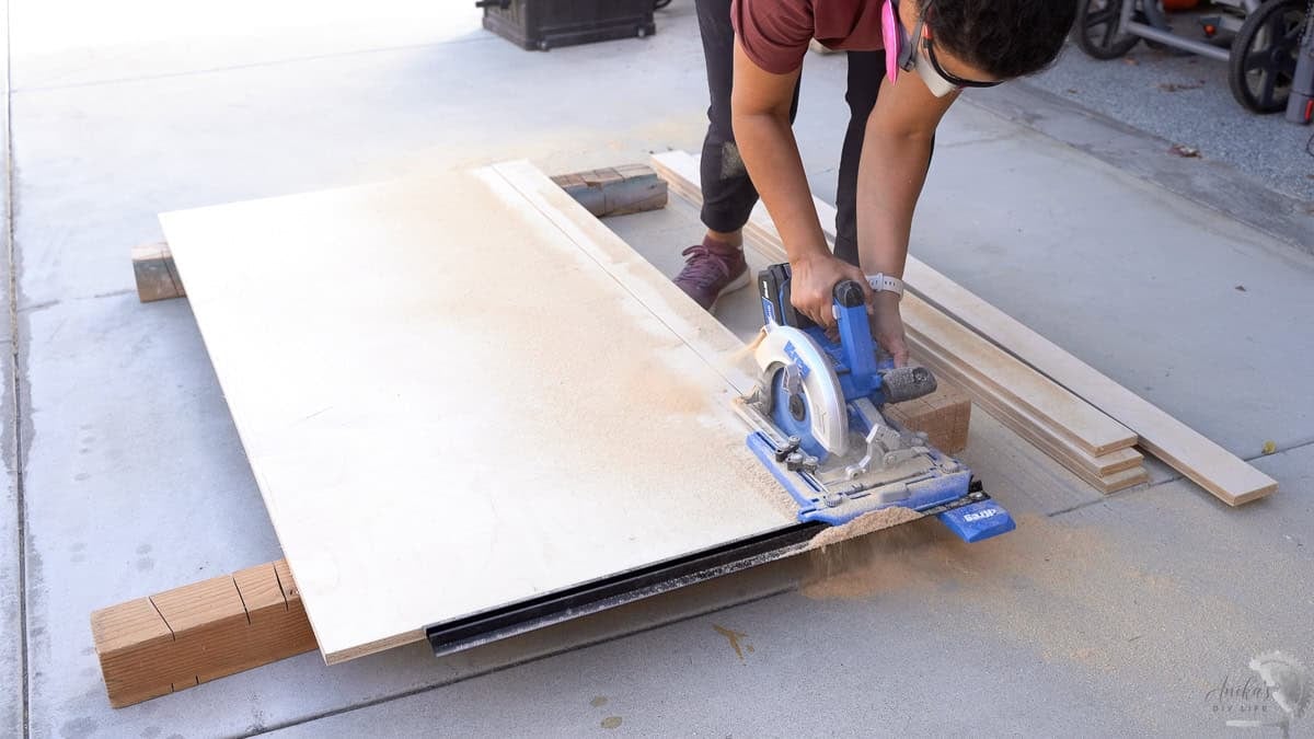 Woman cutting sheet of plywood in driveway with a circular saw and kreg rip cut