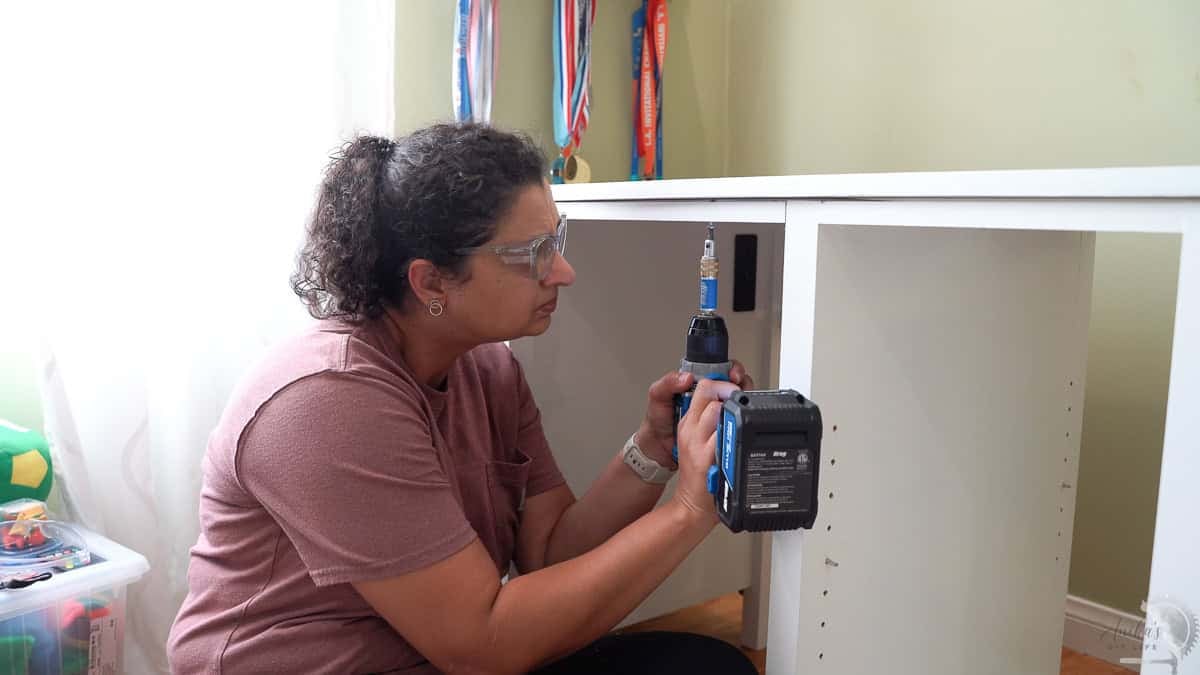 Anika attaching the top to the braces using countersunk screws.