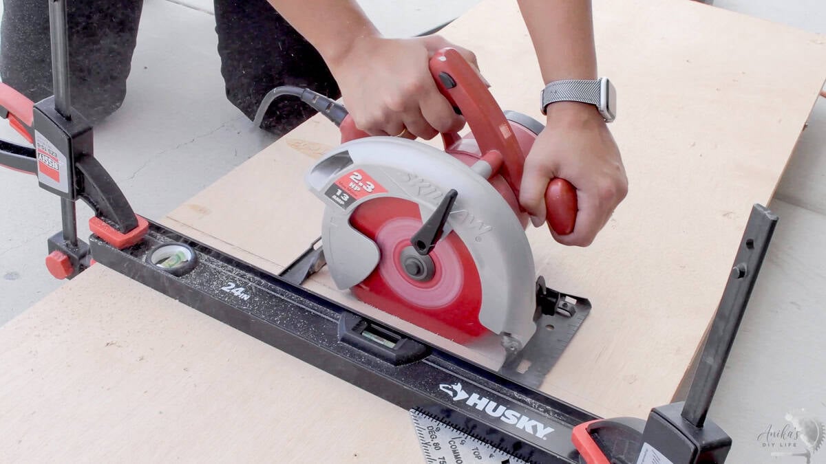Using a Skil circular saw with a straight edge guide to make a long rip cut on a sheet of plywood.