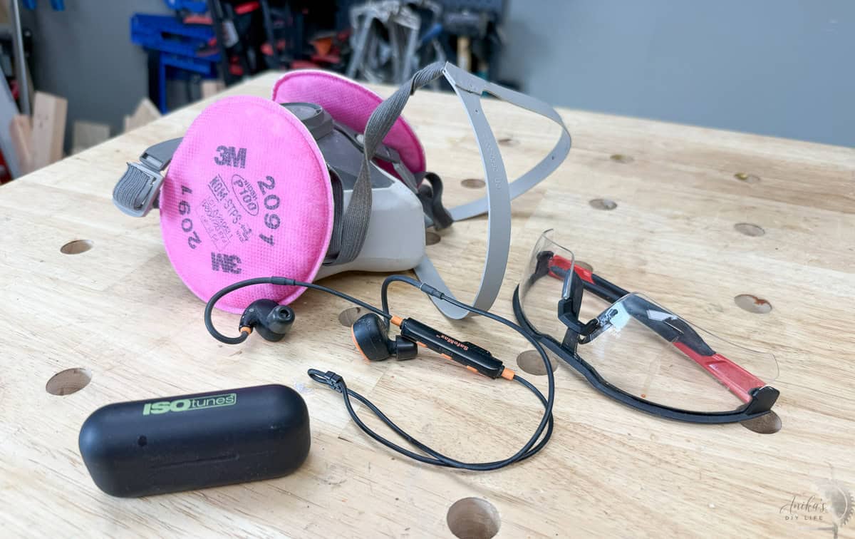 Essential woodworking safety gear for beginners including a 3M respirator for dust protection , protective eye goggles , and ISOtunes wireless earbuds for hearing protection.