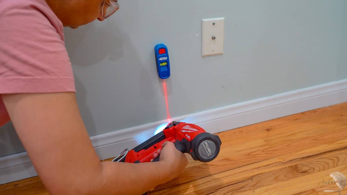 Attaching baseboards to the wall using a nail gun and a stud finder