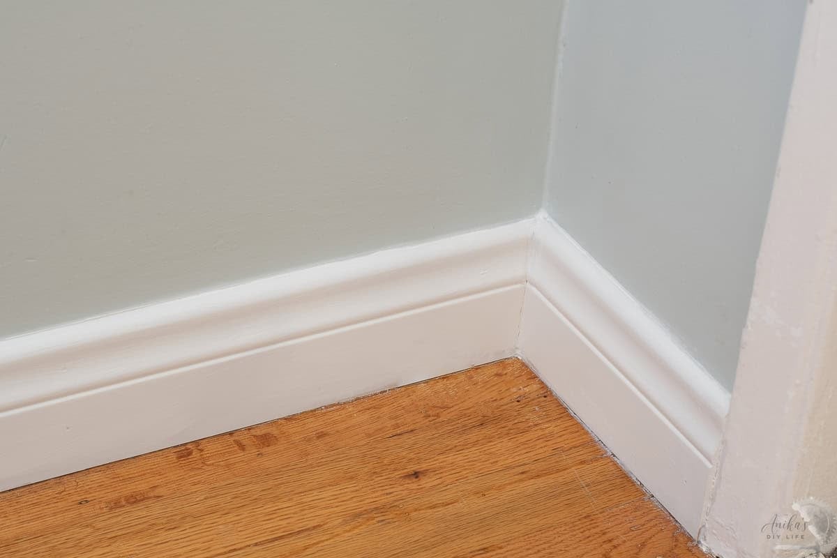 inside corner with seamless baseboards installation in room with blue walls and wooden floors