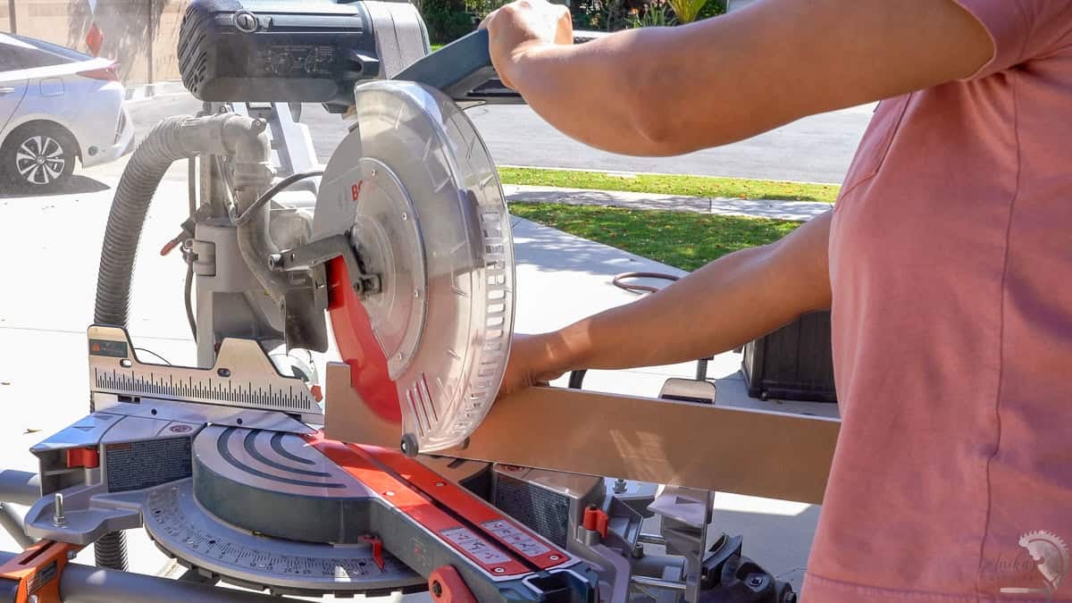 Cutting a 45 degree angle on a baseboard with a miter saw.