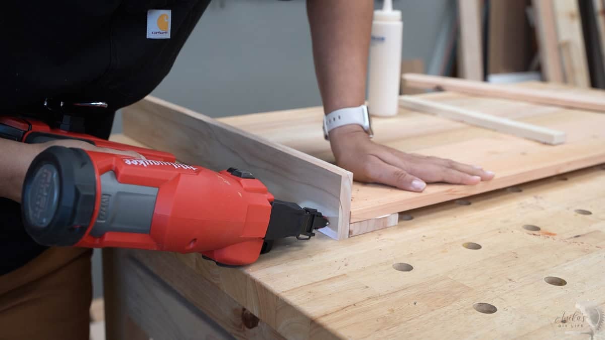 Attaching the next set of legs to the side panels using a red brad nailer