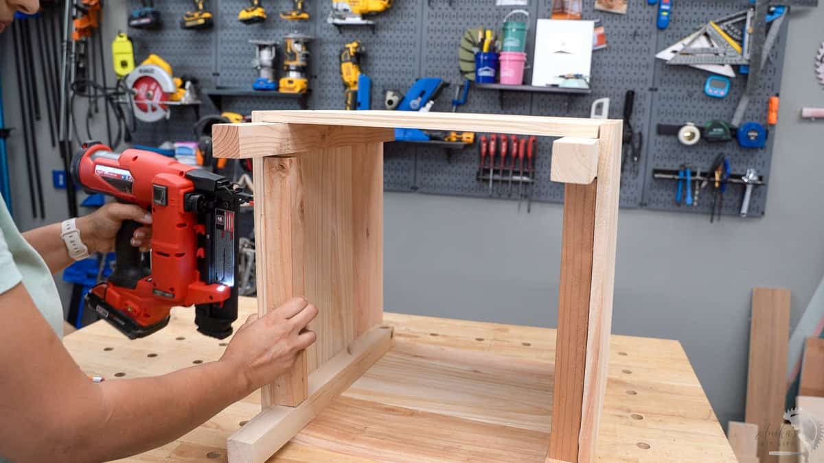 Attaching 2x2 supports to the side of the planter box with a nail gun.