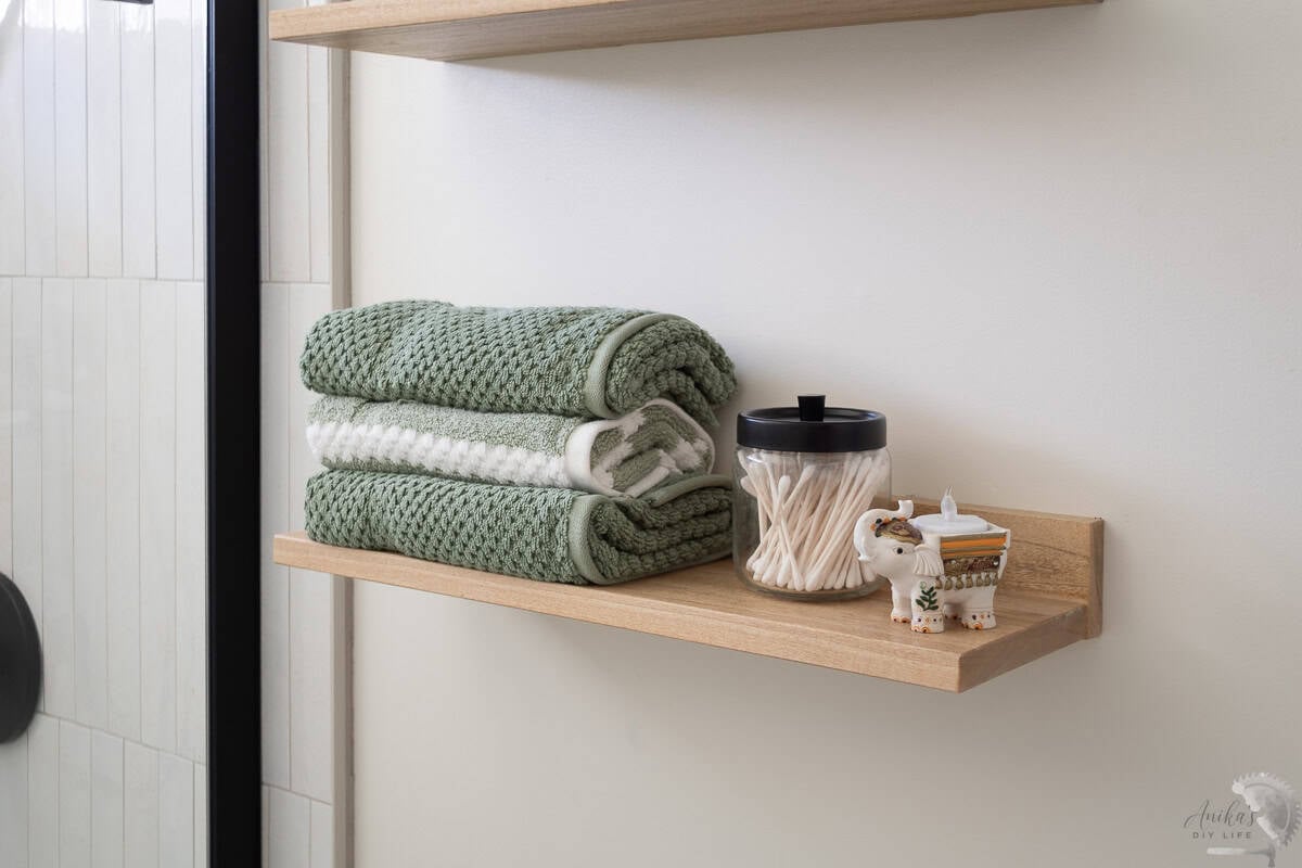 Close up of the easiest diy floating shelf iin bathroom with towels and decor.