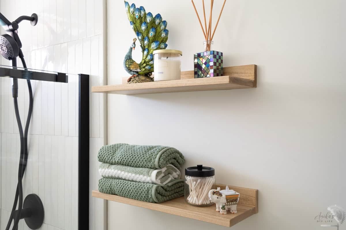 two brown Easy DIY floating shelves in a bathroom with towels and decor items on them
