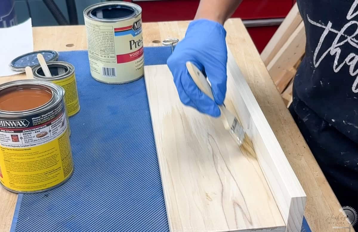 applying prestain conditioner to the wood for the shelf