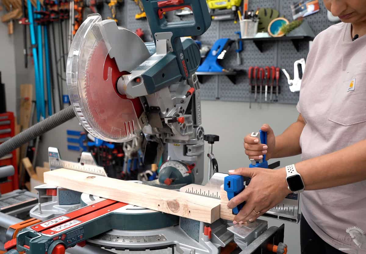 Anika clamping a stop block to the miter saw to make repeated cuts