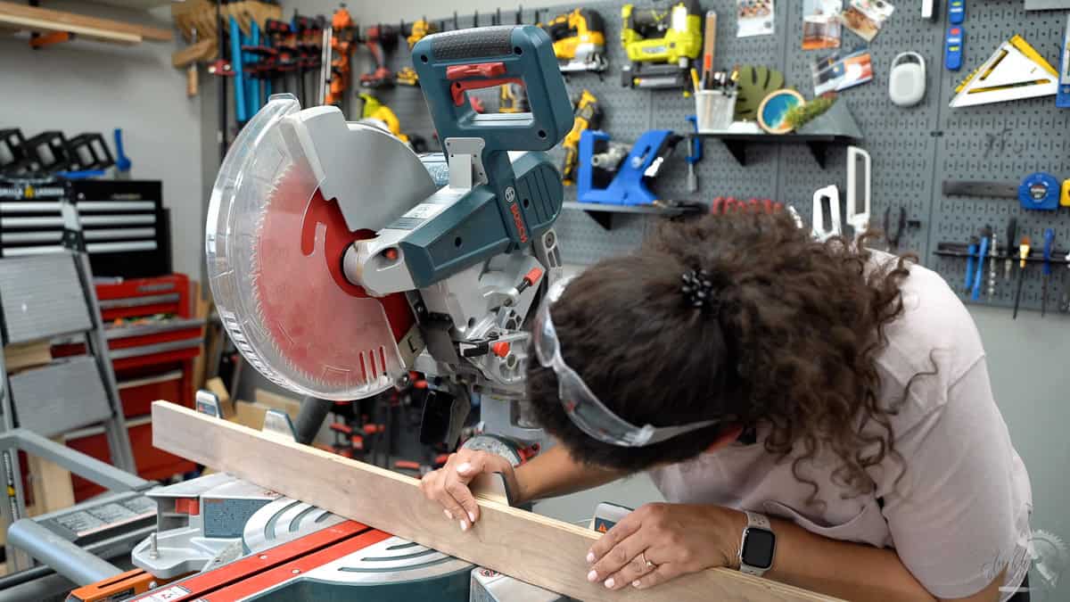 Anika attaching the plywood strip to the miter saw